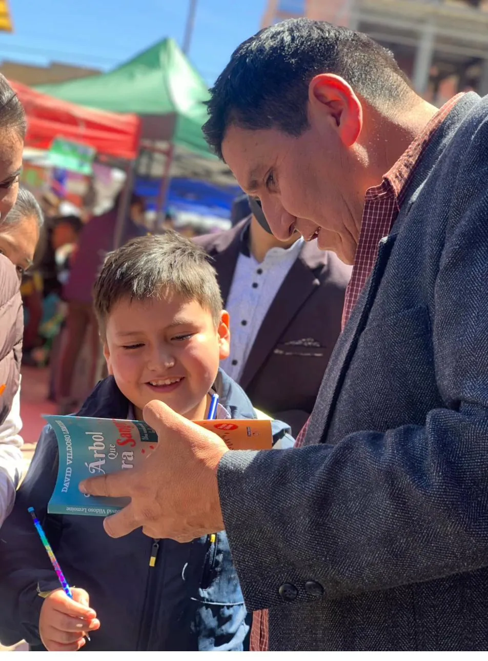 David Vildoso signing a book for a young boy at an outdoor fair