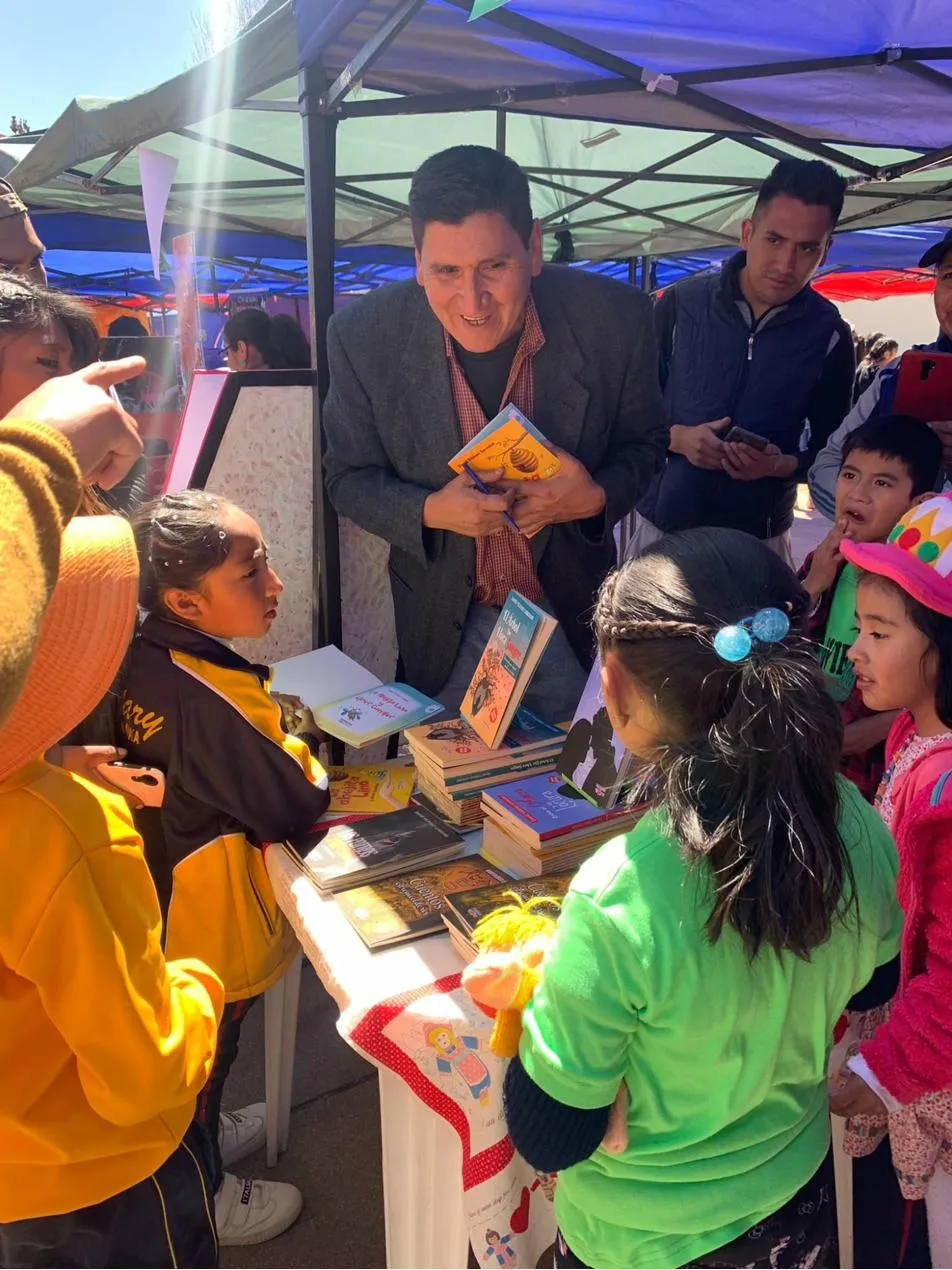 David Vildoso firmando libros para niños en una feria