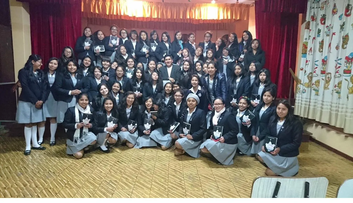 David Vildoso with schoolgirls holding his books at a literary event
